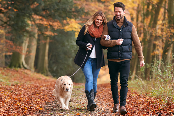 Happy couple walking their dog through a wood in the Lake District